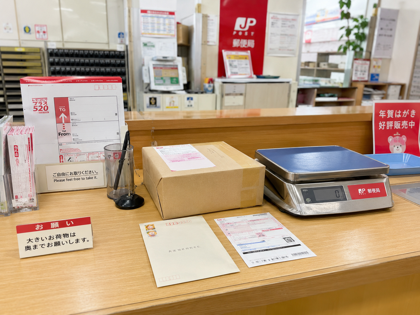 郵便局の窓口、手紙、小包、はかり、切手が並ぶ様子
