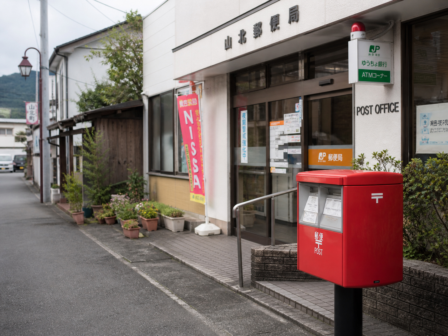 小さな町の郵便局、赤いポスト、入口のガラス戸、柔らかな午後の光